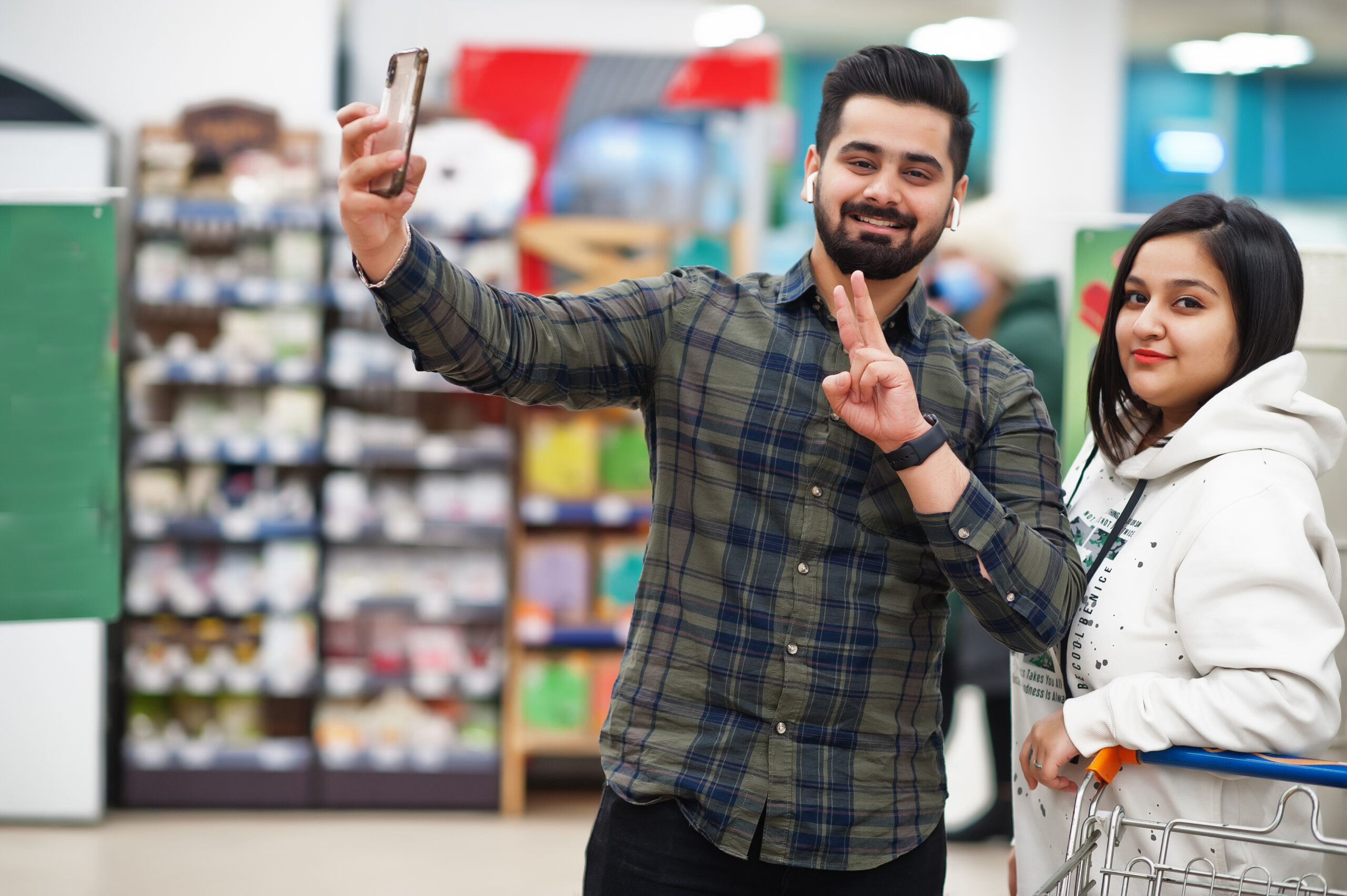 Asian couple wear shopping together in supermarket, making selfie by phone.